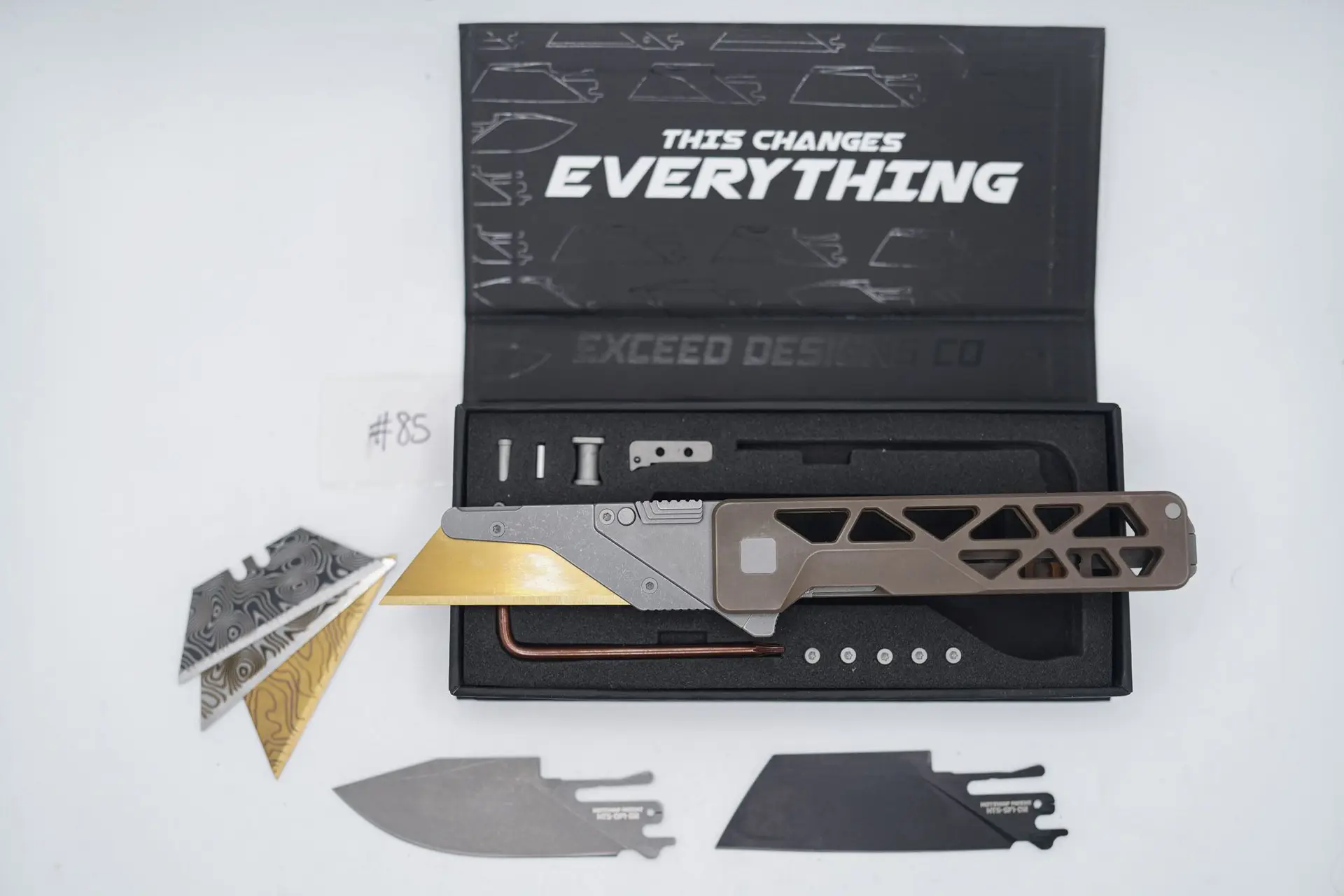 BUILD #85 — Condition 8/10 — TiRant ULTRA Skeleton ‘SKULTRA’ Centurion Bronze W/Blasted Grey Hardware + Original Box W/Spare Grey Blasted Hardware Kit / Lock Bar insert + FULL-FRAG Stonewashed Dark Grey Ti Backspacer + D2 Jet-Black Sheepsfoot Hotswap Blade + D2 Stonewashed Drop Point Hotswap Blade + 3X Custom Laser Engraved Razor Blades